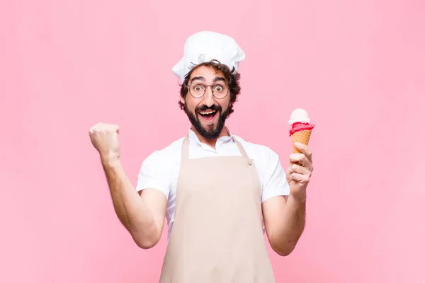 ピンクの壁にアイスクリームをかけた若いクレイジーシェフの男 — ストック写真
