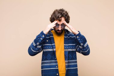 Genç çılgın havalı adam stresli ve hayal kırıklığına uğramış görünüyor, baskı altında çalışıyor, başı ağrıyor ve düz duvara karşı sorunları var.