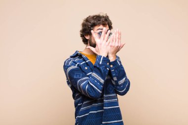 Genç, çılgın, havalı adam korkmuş ya da utanmış hissediyor. Gözleri yarı kapalı, elleri düz duvara yaslanmış, dikizliyor ya da dikizliyor.