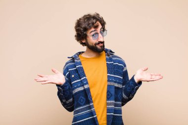 Genç çılgın havalı adam şaşkın ve kafası karışmış hissediyor, doğru cevap veya karardan emin değil, düz duvara karşı bir seçim yapmaya çalışıyor.