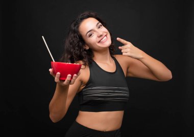 Genç, güzel bir kadın, kendine güvenerek gülümsüyor. Kendi gülüşünü gösteriyor. Pozitif, rahat, tatmin olmuş bir tavır.