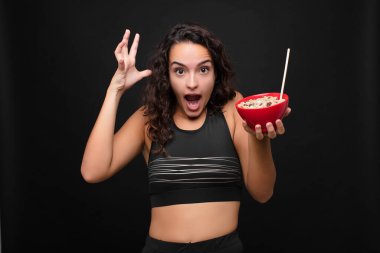 Genç ve güzel bir kadın ellerini havaya kaldırarak bağırıyor. Öfkeli, sinirli, stresli ve üzgün hissediyor. Kahvaltıda sağlıklı bir kase yiyor.