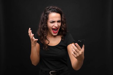 Genç ve güzel bir kadın sinirli, sinirli ve hayal kırıklığına uğramış görünüyor. Elinde akıllı telefon tutmanın nesi yanlış? 