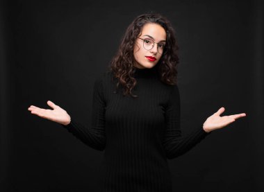 Genç güzel kadın şaşkın ve kafası karışmış hissediyor. Doğru cevap ya da karardan emin değil. Siyah arka plana karşı bir seçim yapmaya çalışıyor..