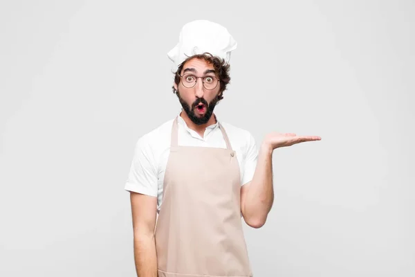 Joven Chef Loco Mirando Sorprendido Sorprendido Con Mandíbula Caída Sosteniendo — Foto de Stock