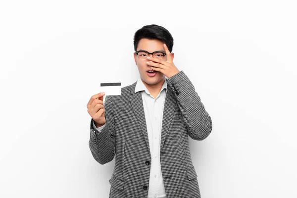 年轻的日本男人看上去震惊 害怕或害怕 用手捂住脸 用手指偷看 信用卡概念 — 图库照片