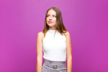 Kızıl saçlı güzel bir kadın mutlu, gururlu ve umutlu, merak eden ya da düşünen, mor duvarlara karşı çapraz kollarıyla boşluğu arayan