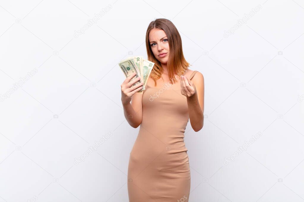 red head pretty woman looking arrogant, successful, positive and proud, pointing to self with dollar banknotes