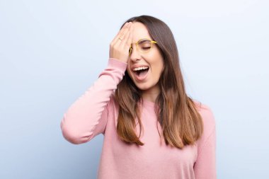 Genç, güzel bir kadın uykulu, sıkılmış ve esniyor, baş ağrısı ve yüzünün yarısını mavi duvarla kaplayan bir el