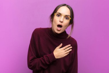 Genç ve güzel bir kadın şok olmuş ve şaşırmış hissediyor, gülümsüyor, el ele tutuşuyor, o olmaktan mutlu ya da mor duvara karşı minnettarlık gösteriyor.