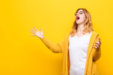 Sarı duvara karşı romantik, sanatsal ve tutkulu hisseden genç, sarışın bir kadın opera ya da konserde şarkı söylüyor ya da şarkı söylüyor.