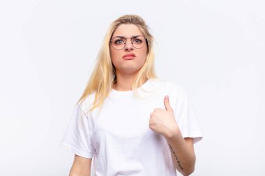 Genç, güzel, sarışın bir kadın şaşkın, şaşkın ve güvensiz hissediyor. Kendini gösterip kim olduğumu soruyor, ben mi? Beyaz duvara yaslan