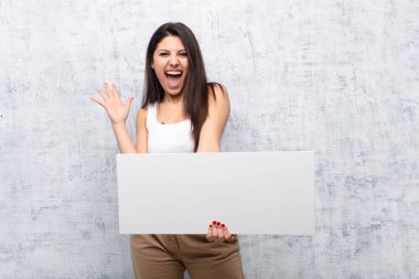 Genç ve güzel bir kadın grunge duvarına pankart asıyor.