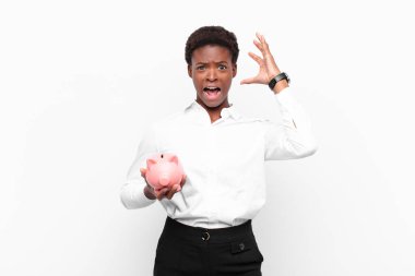 Genç ve güzel siyahi bir kadın ellerini havaya kaldırıp bağırıyor. Öfkeli, sinirli, stresli ve üzgün bir şekilde kumbarayı tutuyor.