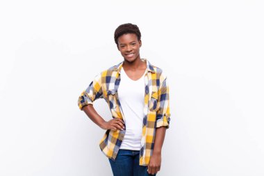 Genç ve güzel siyah kadın kameraya çapraz kollarıyla gülümsüyor ve mutlu, kendinden emin, tatmin olmuş bir ifade, yan bakış.