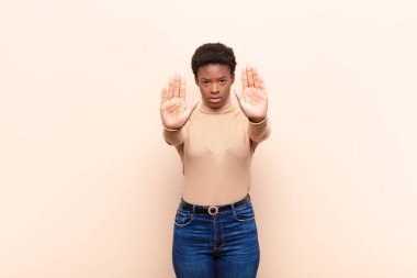 Genç siyah kadın ciddi görünüyor, mutsuz, kızgın ve hoşnutsuz giriş yasaklandı ya da her iki avuçta da dur diyor.