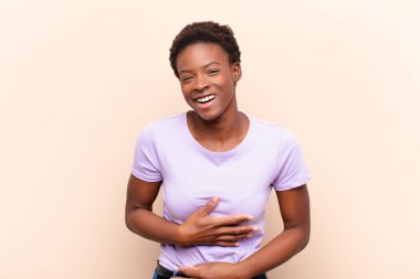 Genç, güzel, siyah bir kadın komik bir şakaya yüksek sesle gülüyor, mutlu ve neşeli hissediyor, eğleniyor.