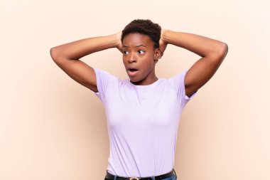 Korkunç bir hata yüzünden dehşete düşmüş ve şok olmuş görünen ağzı açık, genç, siyah bir kadın, el ele tutuşuyor.