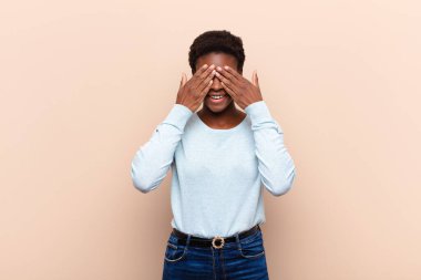 Genç ve güzel siyah kadın gülümsüyor ve mutlu hissediyor, iki eliyle gözlerini kapatıyor ve inanılmaz bir sürpriz bekliyor.