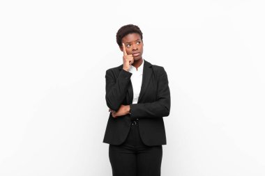 Genç, güzel, siyah bir kadın. Yoğunlaşmış bakışları var. Şüpheli bir ifadeyle yukarı ve yana beyaz duvara bakıyor.