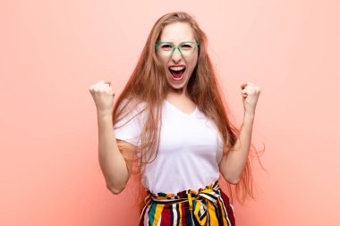 Genç sarışın kadın mutlu, pozitif ve başarılı hissediyor, zaferi, başarıları veya iyi şansı kutluyor.