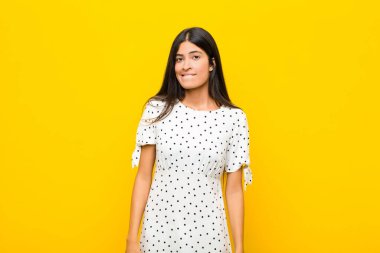 Genç, güzel, Latin bir kadın kafası karışmış ve kafası karışmış görünüyor. Sinirli bir hareketle dudağını ısırıyor. Düz duvara karşı sorunun cevabını bilmiyor.