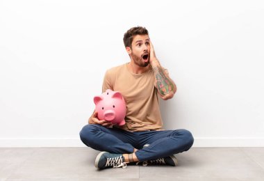 Mutlu, heyecanlı ve şaşırmış hissediyorum, iki elinle bir kumbara tutarken yana bakıyorum.