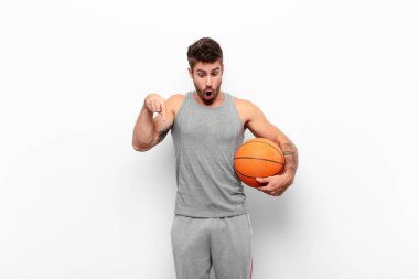 Genç yakışıklı adam şok olmuş, ağzı açık ve hayret içinde, inançsızlık ve şaşkınlıkla bakıyor ve bir basketbol topu tutuyor..