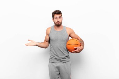 Genç yakışıklı adam şaşkın ve şaşkın hissediyor, doğru cevap ya da karardan emin değil, basketbol topunu tutarak bir seçim yapmaya çalışıyor..