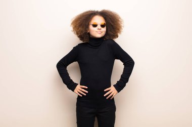 Afrikalı Amerikalı küçük kız düz duvara yaslanmış. cool konsept