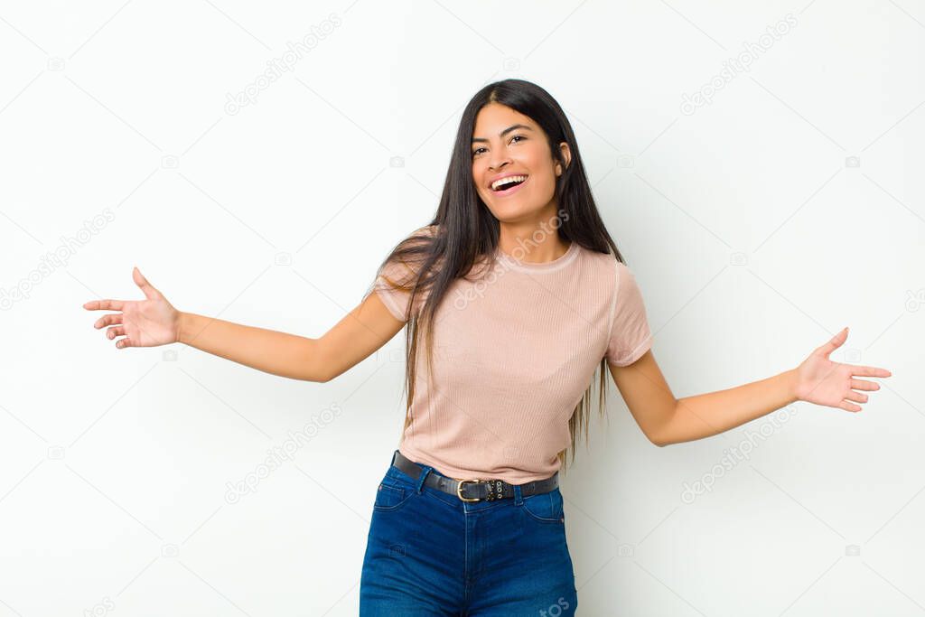 young pretty latin woman looking happy, arrogant, proud and self satisfied, feeling like a number one against flat wall