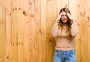 Genç sarışın kadın stresli ve hayal kırıklığına uğramış görünüyor. Baskı altında, baş ağrısı ve sorunlarıyla çalışıyor.