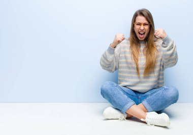 Genç sarışın kadın kendini mutlu, pozitif ve başarılı hissediyor zaferi kutluyor, başarıları kutluyor ya da yerde iyi şanslar diliyor.