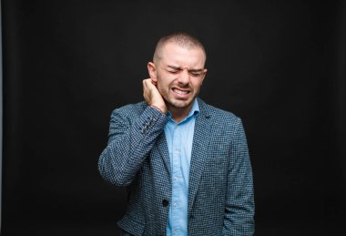 Genç işadamı stresli, hayal kırıklığına uğramış ve yorgun hissediyor. Endişeli ve sorunlu bir bakışla düz duvara yaslanıyor.