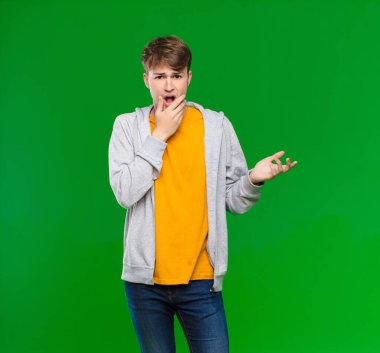 Genç sarışın adam ağzı ve gözleri sonuna kadar açık ve eli çenesinde, kötü bir şokta, kroma anahtarına karşı ne ya da wow diyor