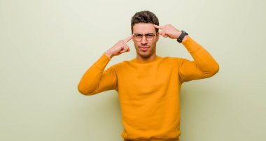 Ciddi ve konsantre görünümlü genç bir Arap adam, düz duvara karşı meydan okuyucu bir sorun düşünüyor ve beyin fırtınası yapıyor.