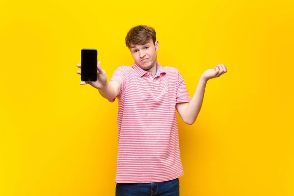 一个拿着智能手机的金发年轻人 — 图库照片