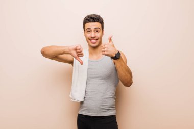 Genç Arap adam kafası karışmış, bilgisiz ve kararsız hissediyor, iyi ve kötü seçenekleri farklı seçeneklerle tartıyor. spor konsepti