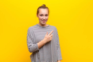 Genç sarışın güzel kız gülümsüyor ve arkadaş canlısı görünüyor, onuncu ya da onuncu numarayı gösteriyor, sarı duvara doğru sayıyor.