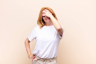 Orta yaşlı bir kadın gülüyor ve alnına şaplak atıyor. Unuttum ya da aptalca bir hataydı. 