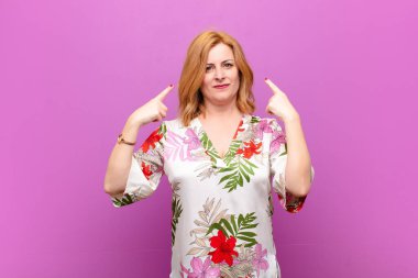 Kötü tavırlı orta yaşlı bir kadın gururlu ve agresif görünüyor, yukarıyı gösteriyor ya da elleriyle alay işareti yapıyor.