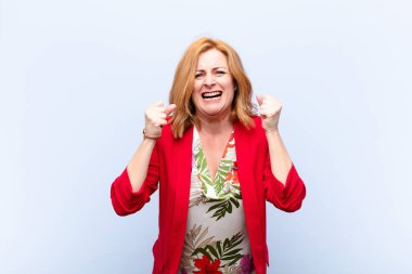 Orta yaşlı bir kadın sinirli, sinirli, kızgın bakışlar ve sıkı yumruklarla bağırıyor. Öfkeli hissediyor.