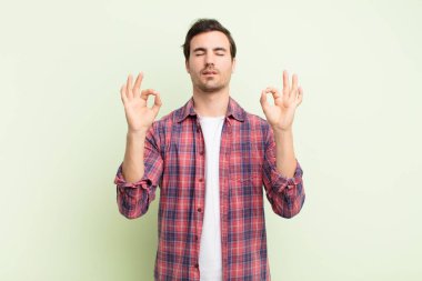 Genç yakışıklı adam konsantre olmuş ve meditasyon yapıyor, kendini tatmin olmuş ve rahatlamış hissediyor, düşünüyor ya da bir seçim yapıyor.