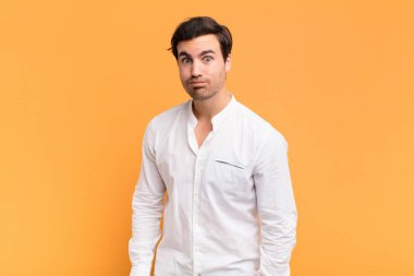 Aptal, çılgın, şaşkın bir ifadeyle genç yakışıklı adam, yanakları şişmiş, doldurulmuş, şişman ve yemekle dolu.