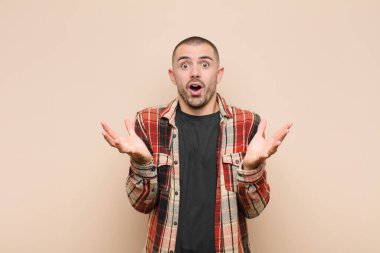 Genç yakışıklı adam şok olmuş ve şaşırmış, endişeli ve paniklemiş, stresli ve dehşete kapılmış bir şekilde düz duvara bakıyor.