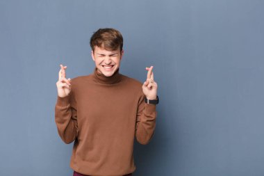 Genç sarışın adam gergin ve umutlu, şans diliyor ve dua ediyor.