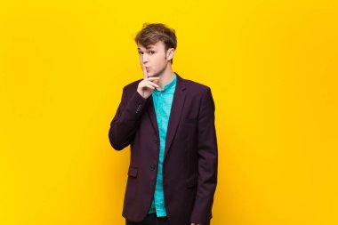 Genç sarışın adam sessizlik ve sessizlik istiyor, parmağıyla ağzının önünde işaret ediyor, 