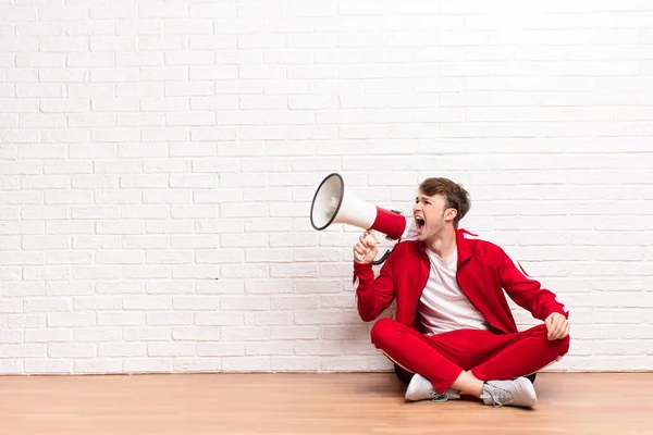 Junger Blonder Mann Sitzt Mit Megafon Auf Dem Boden — Stockfoto