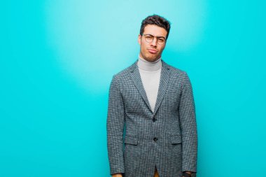 Genç Arap bir adam üzgün ve mızmız görünüyor. Mavi duvara karşı olumsuz ve hayal kırıklığına uğramış bir tavırla ağlıyor.