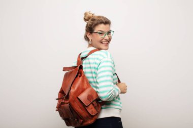 Deri çantalı, düz duvara yaslanmış genç Latin bir kadın.